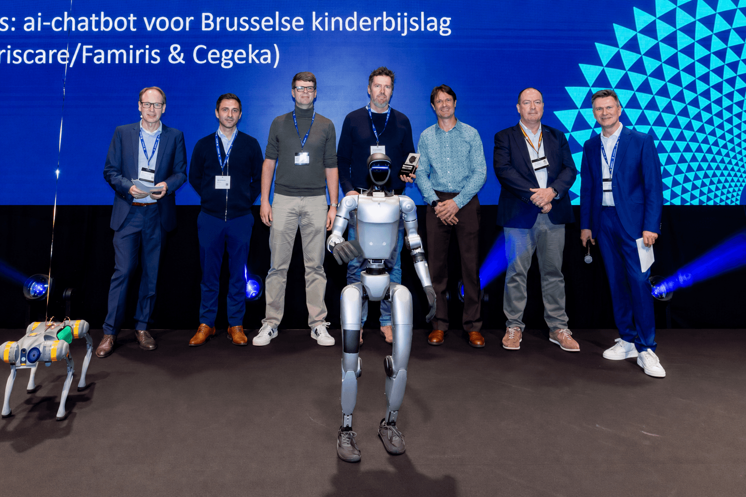 Humanoid robot en robothond op het podium tijdens de Computable Awards, omringd door het team