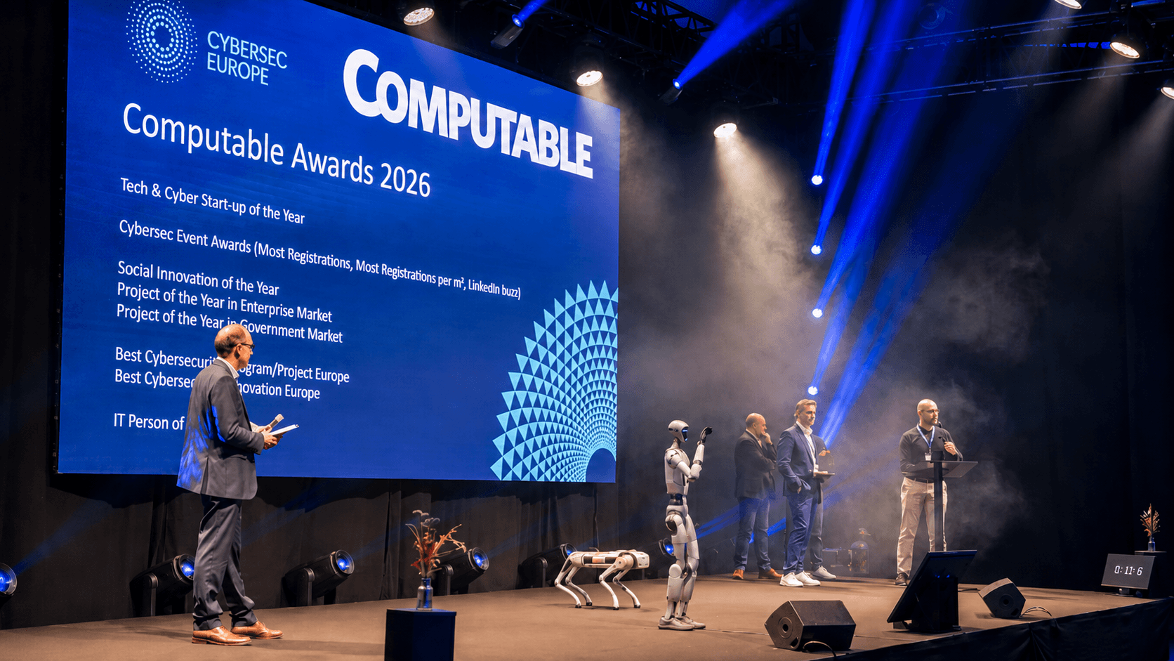 Robothond en humanoid robot op het podium tijdens een live awardshow, met presentator en publiek in dramatisch blauw lichtspel